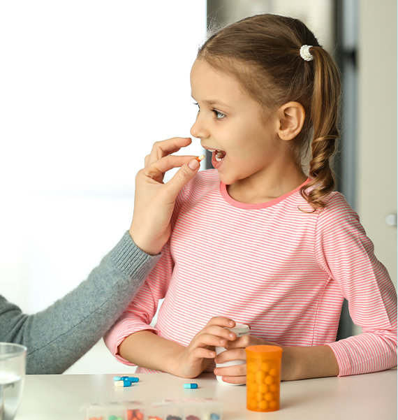 Mother giving happy child medication that is personalized and child-friendly compounded medication.